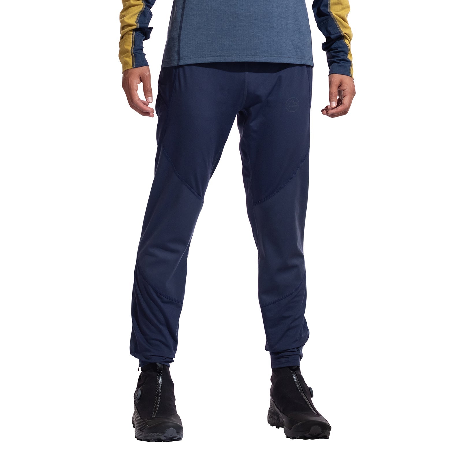 A person wears La Sportiva's Primal Pants Men's (navy), a blue and yellow long-sleeve top, and black hiking boots. Cropped at the shoulders, this image showcases ideal winter or mountain running attire against a plain white background.