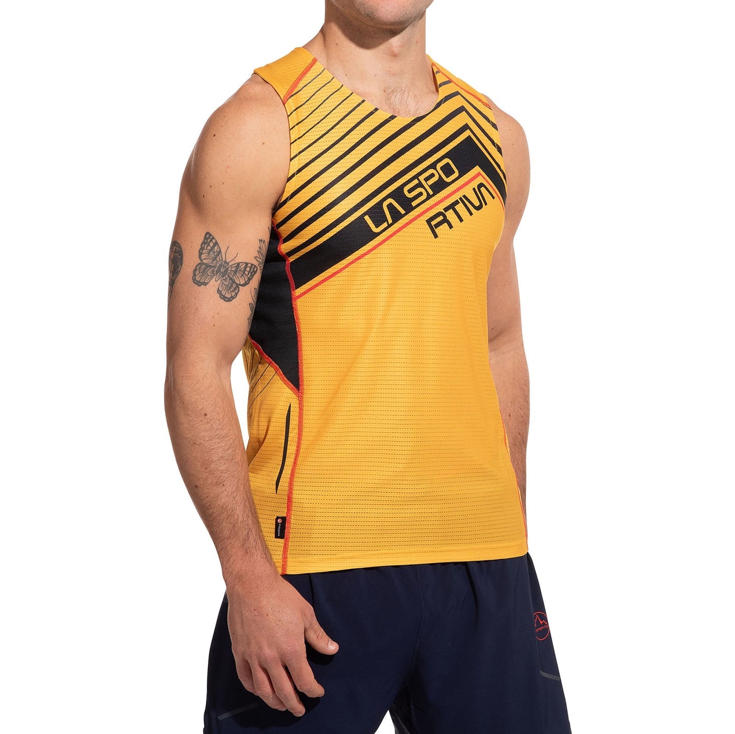 A person in a yellow La Sportiva Slipstream Tank Men's with black and red accents, navy blue shorts, and a visible butterfly tattoo on their left upper arm; the competition-ready sleeveless top fits lightweight. Their face is partially out of frame.