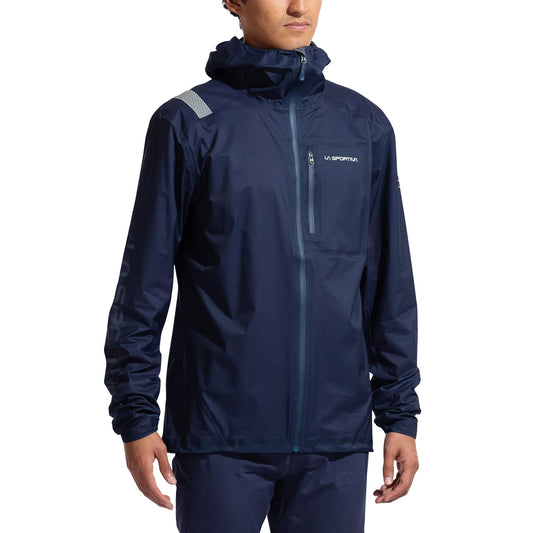 A person wears the La Sportiva Ethereal Pro Jacket Men's in navy blue—a rainproof, hooded shell with a front zipper and reflective details—designed for freedom of movement, standing against a plain white background.