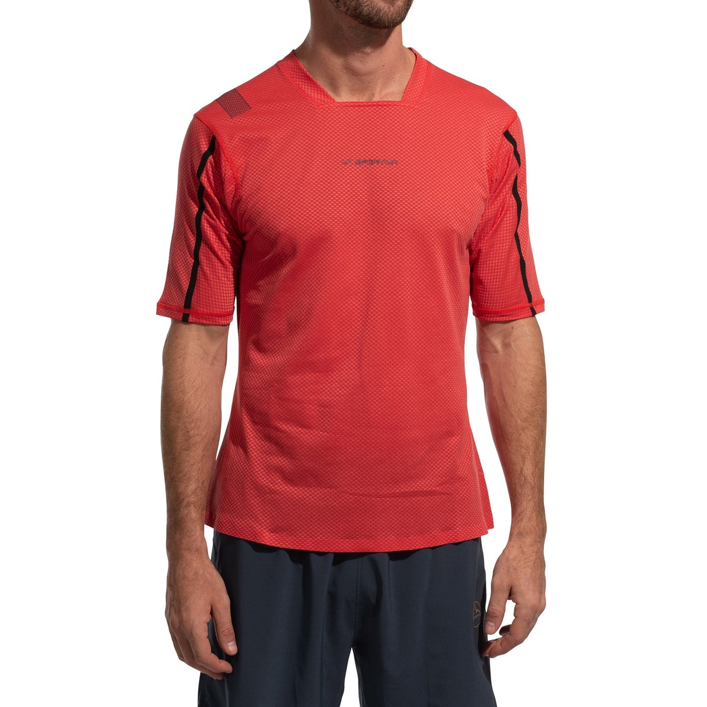 A man wears the La Sportiva Trail Bite T-Shirt Men's in red with black accents and dark shorts, standing facing forward with arms relaxed. His head is partially out of frame.