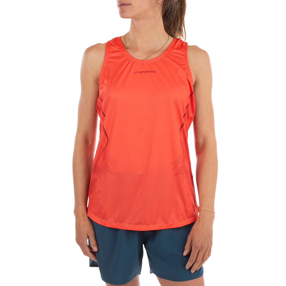 On voit ici une femme portant le débardeur La Sportiva Pacer Tank pour femme, de couleur rouge, confectionné en polyester recyclé, associé à un short bleu, debout devant un fond blanc. Son visage est partiellement masqué, et l'inscription « La Sportiva » figure sur le haut, ce qui en fait un choix idéal pour les séances d'entraînement.