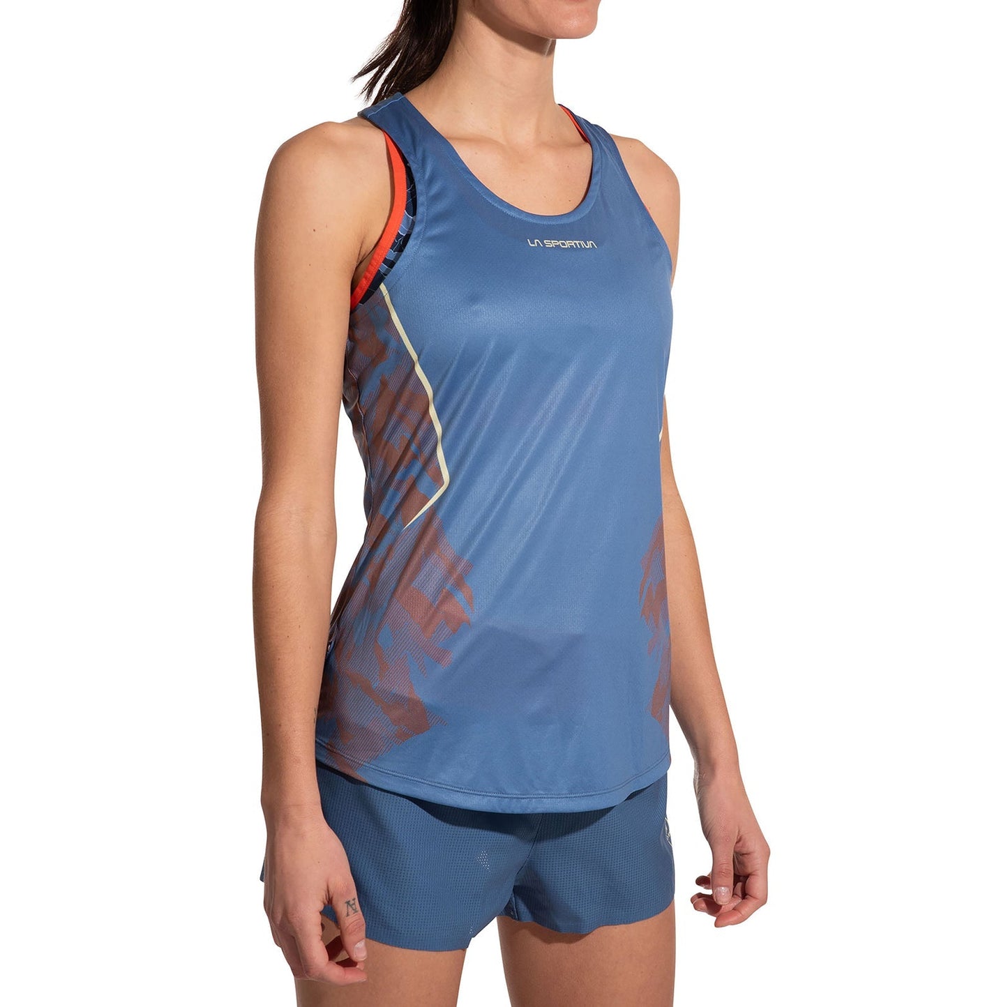 A woman in a La Sportiva Pacer Tank Women's and matching shorts, made from recycled polyester, poses against a white background. The sporty, fitted blue outfit features red and yellow accents for a vibrant athletic look.
