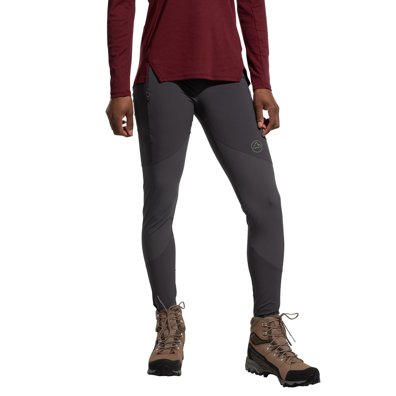 A person wearing a long-sleeve maroon shirt, La Sportiva Camino Tight Pants Women's (2025) in gray, and brown hiking boots stands against a white background. The person's face is not visible.
