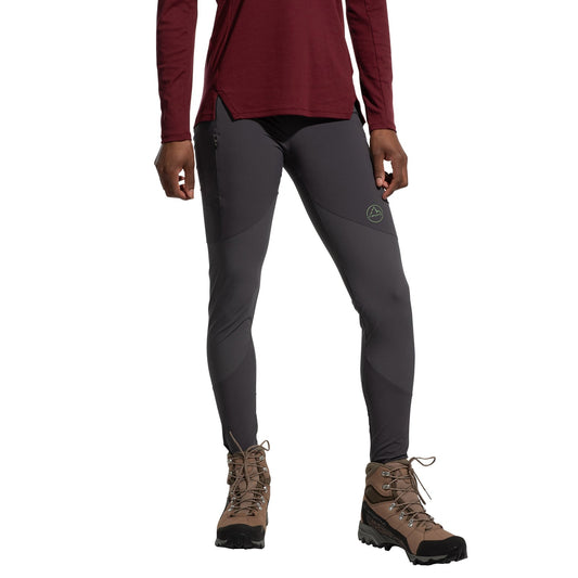 A person wearing a long-sleeve maroon shirt, La Sportiva Camino Tight Pants Women's (2025) in gray, and brown hiking boots stands against a white background. The person's face is not visible.