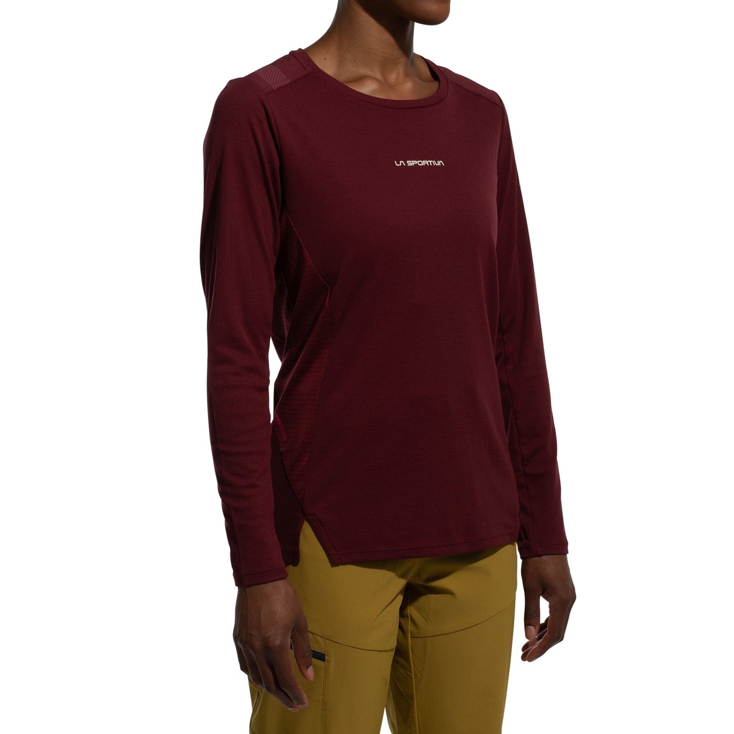A person wearing a dark red La Sportiva Beyond Long Sleeve Women's (2025) top and mustard yellow pants stands against a plain white background. The top features Polartec Delta Cooling Fabric. The face is not visible.