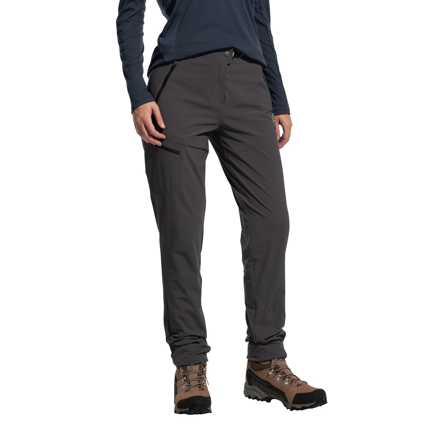 A person wears La Sportiva West Crest Pants Women's (2025), featuring zippered pockets, with a navy long-sleeve top and brown hiking boots, standing against a plain white background with hands relaxed at their sides.