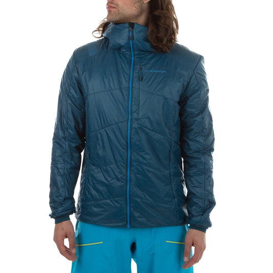 A man in a teal blue La Sportiva Alpine Guide Primaloft Hoody Men's (2024) with high collar and zippered chest pocket, plus bright blue pants, stands slightly turned against a plain white background. The jacket is lightweight and breathable.