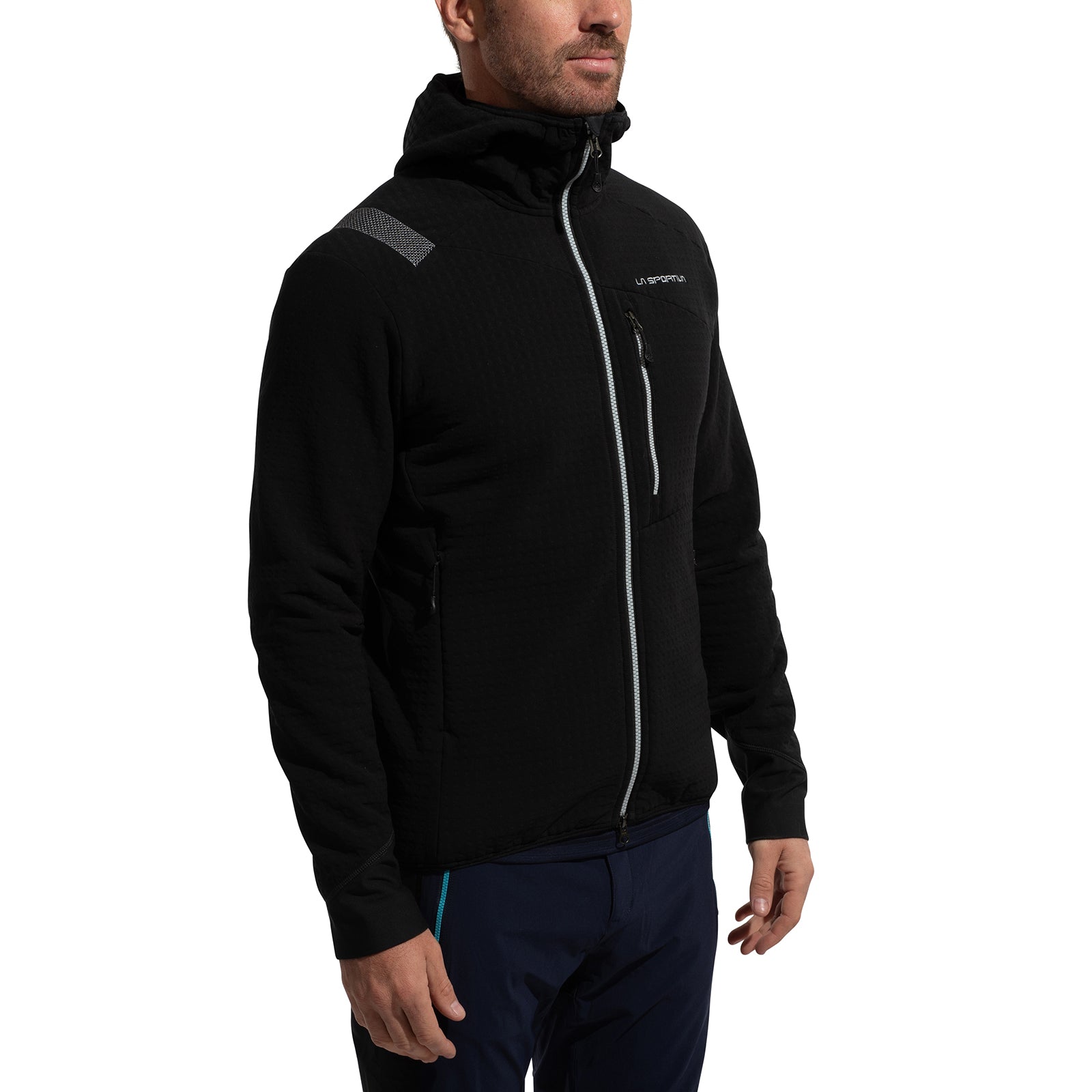 A man wears the La Sportiva Bristen Thermal Hoody Men's in black, featuring two zippered pockets, a hood, small chest logo, and reflective shoulder patch; perfect for outdoor activities. He stands against a white background.
