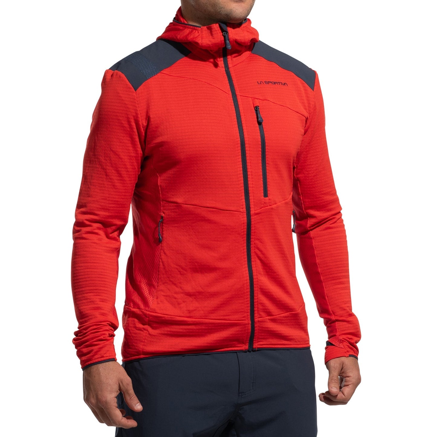 A man wears the La Sportiva Aequilibrium Thermal Hoody Men's (2025), a bright red mountaineering midlayer with black shoulder accents and zippered pockets, standing with arms relaxed against a white background.