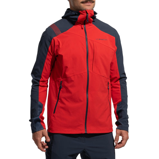 A person wearing the La Sportiva Aequilibrium Speed Jacket Men's (2025) in red and dark navy, featuring breathable fabric and black zippers, stands with hands relaxed by their sides against a plain white background, showing only torso and lower face.