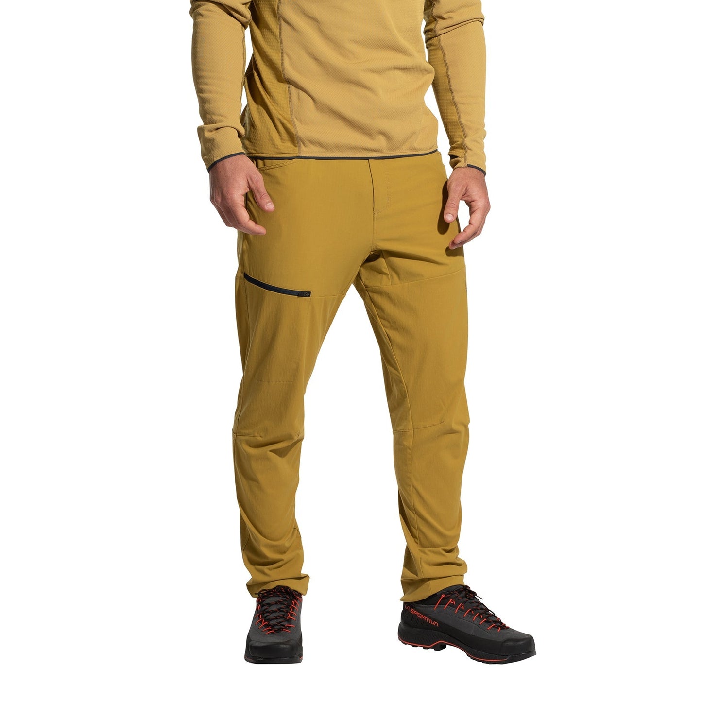 A person wears La Sportiva Machina Tech Pants Men's (2025) in mustard yellow, a matching long-sleeve shirt, and black hiking shoes with red accents, posing against a white background.
