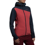 A woman wearing the La Sportiva Bristen Thermal Hoody Women's, a red and navy blue fleece with a textured pattern ideal for outdoor activities, stands against a plain white background.