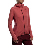 A person wears the La Sportiva Aequilibrium Thermal Hoody Women's (2025), a red Polartec Power Grid zip-up with subtle grid texture and sleeve thumbholes, paired with matching pants, standing against a white background. Face is partially out of frame.