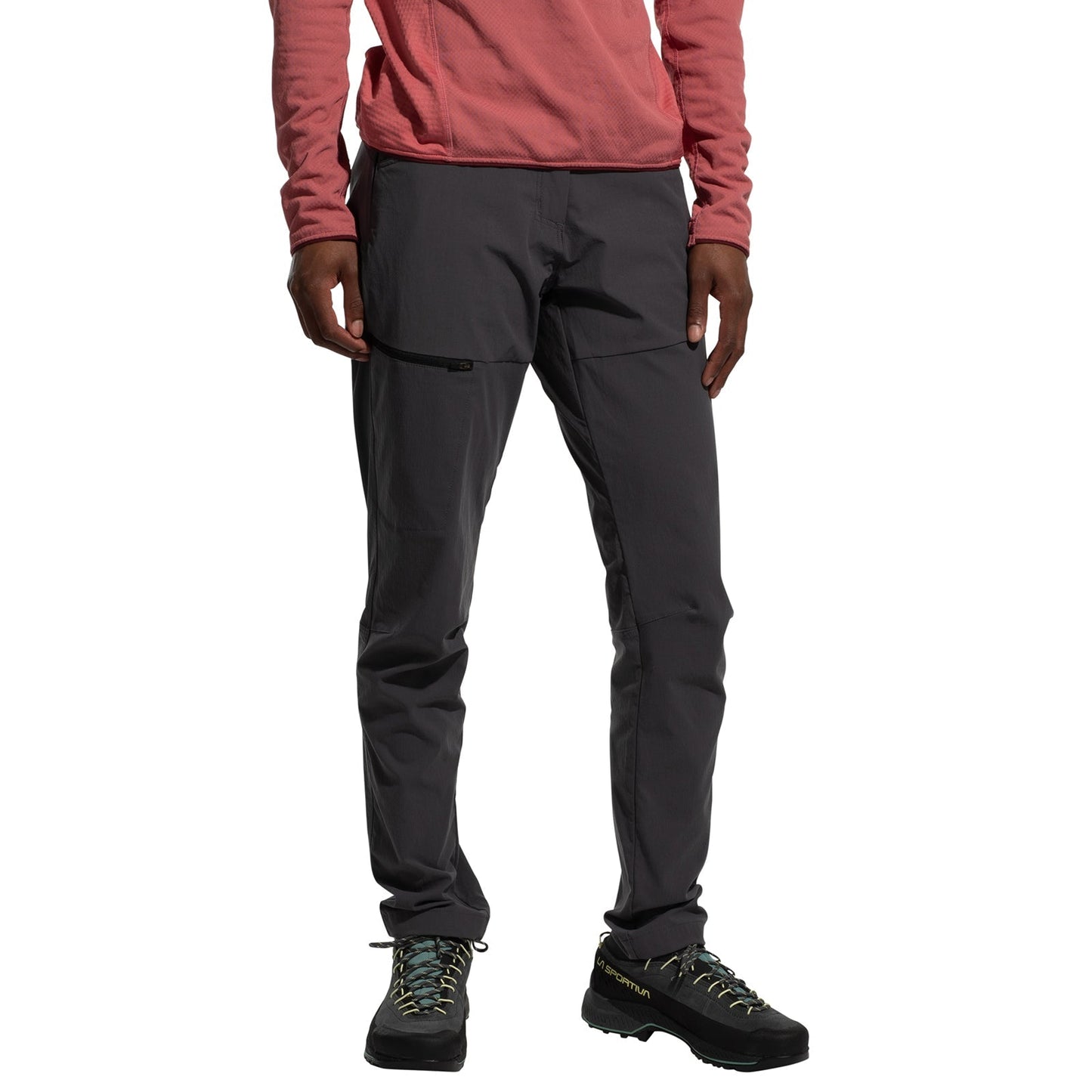 A person stands against a white background, wearing a long-sleeve pink shirt, La Sportiva Machina Tech Pants Women's (2025) in abrasion-resistant dark gray, and black hiking boots with light blue laces. Their head is not visible.