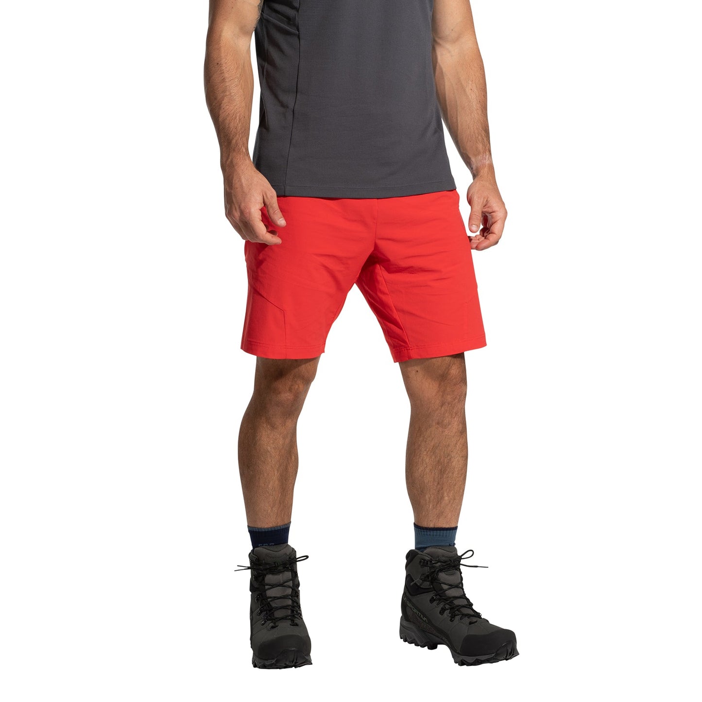 A person wearing a dark gray short-sleeve shirt, La Sportiva Trail Guard Shorts Men's in bright red, navy socks, and black hiking boots stands against a white background. The image is cropped from the shoulders down.