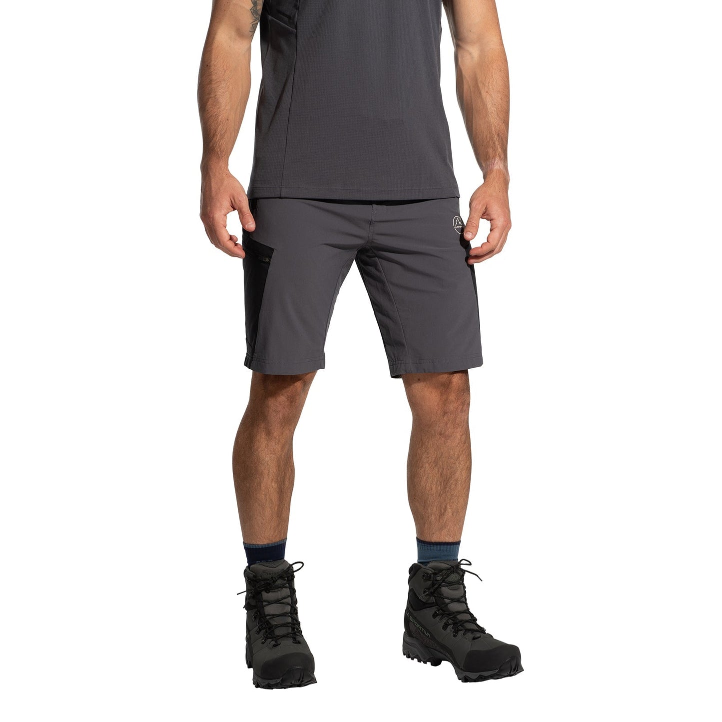 A person wearing a dark gray t-shirt, La Sportiva West Crest Shorts Men's (2025) with pocket details, dark socks, and black hiking boots stands against a white background—perfect for fans of practical outdoor gear.