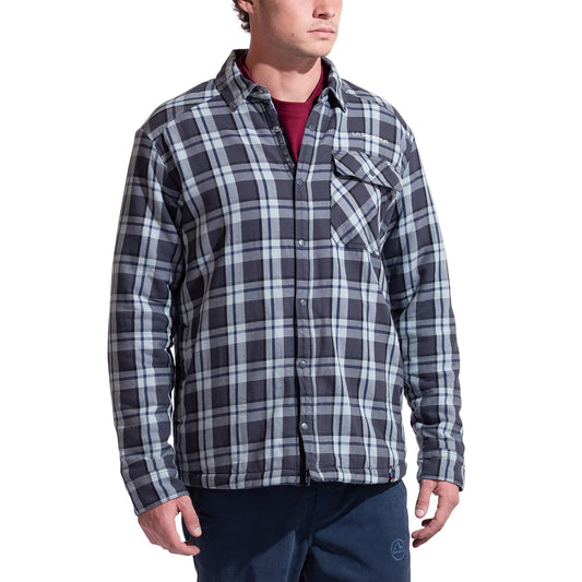 A man wearing the La Sportiva Rambler Lined Flannel Shirt in black, white, and gray plaid with snap buttons over a maroon T-shirt and navy pants stands with his arms relaxed at his sides.