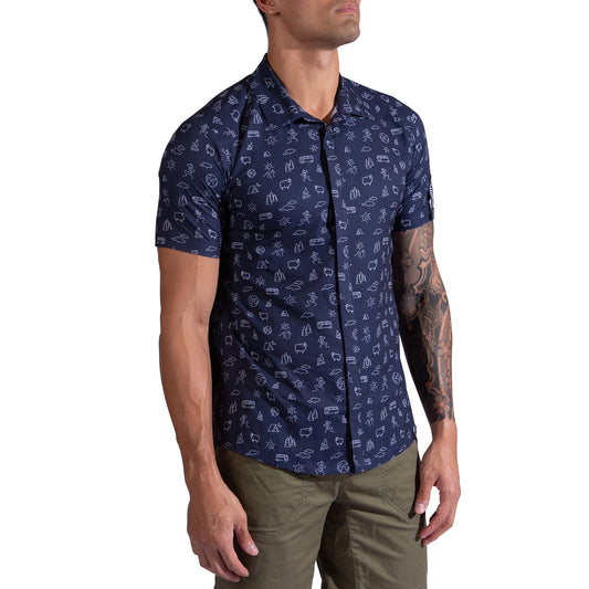 A man wears the La Sportiva Move Tech Shirt—navy, quick-dry, breathable, with small white abstract patterns—and olive green pants, standing with his arms relaxed at his sides.