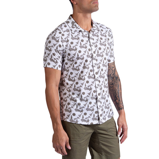 A man stands against a white background wearing the La Sportiva Move Tech Shirt, a breathable, short-sleeve, button-up with a geometric leaf pattern, and olive green shorts. His right arm features a sleeve tattoo.
