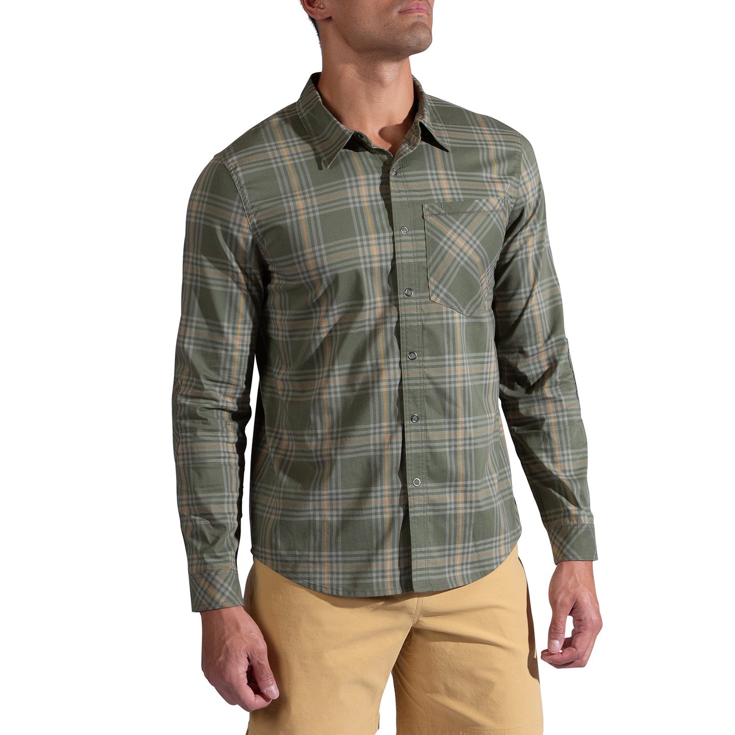 A man wearing the La Sportiva Outer Space Long Sleeve Shirt Men's in green and gray plaid with reinforced elbows and a front pocket, paired with light tan pants, stands against a white background.