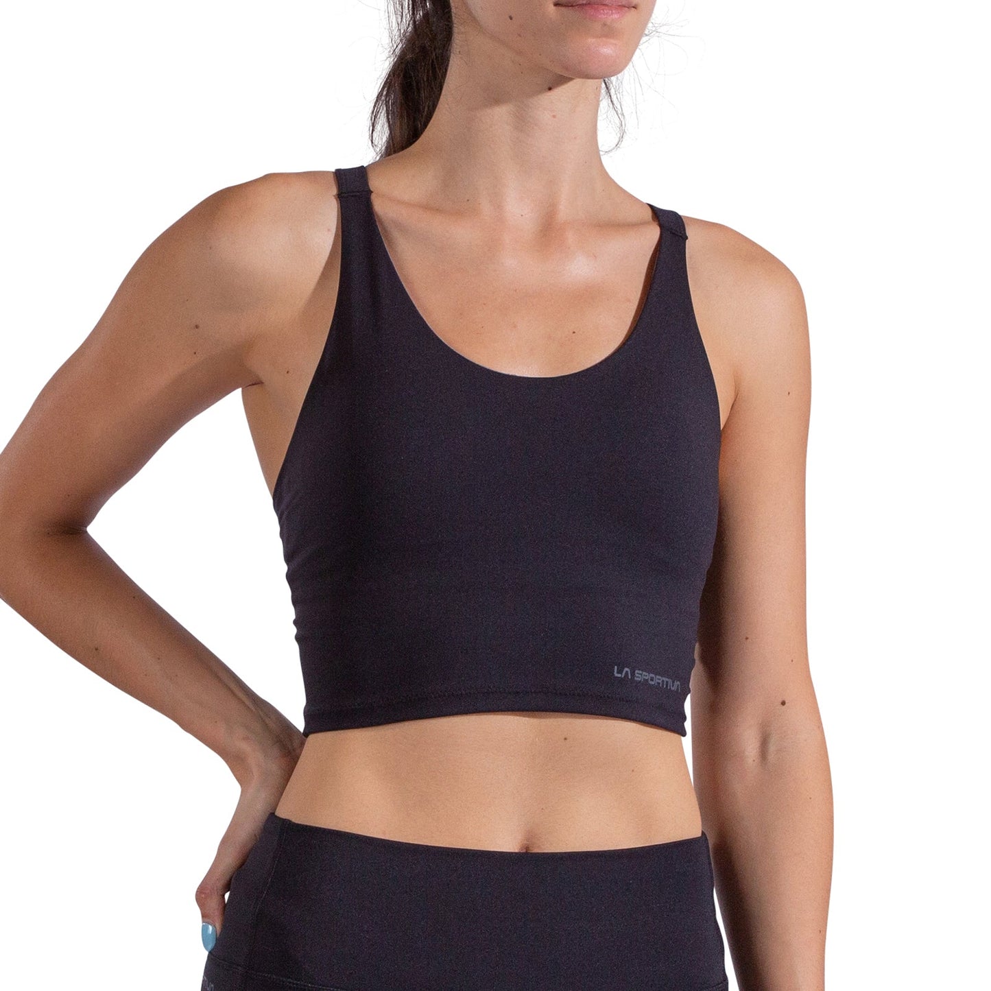A woman wearing the La Sportiva Cosmosis Bra Tank, paired with matching leggings, poses with one hand on her hip against a plain white background.