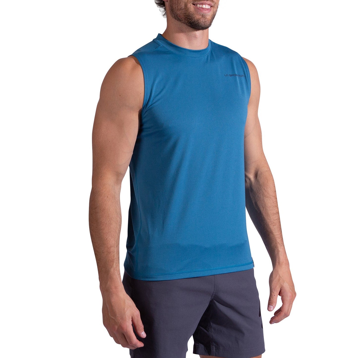 A man wearing the La Sportiva Just Right Tank Men's and black shorts stands smiling against a white background.