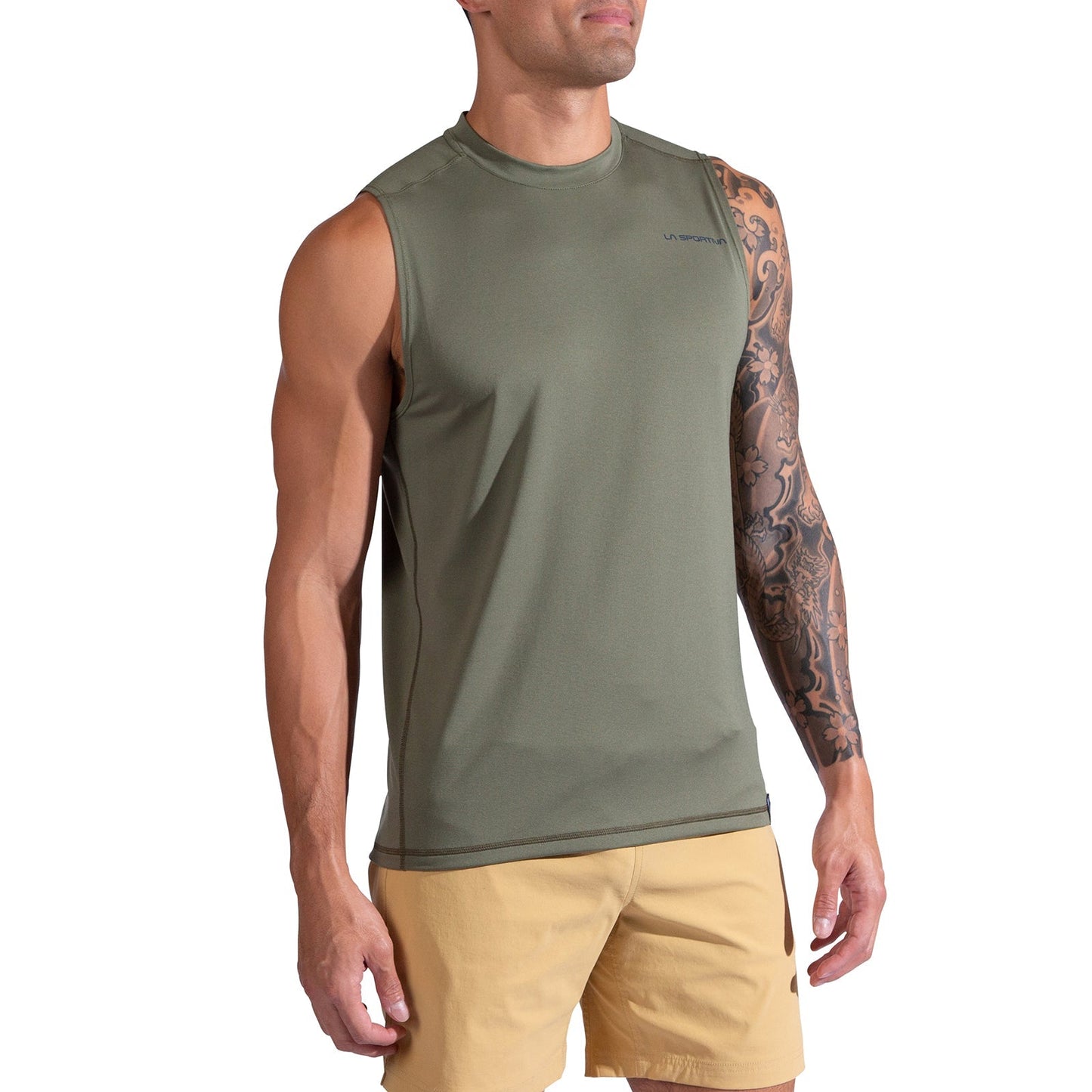 A man in La Sportiva’s Just Right Tank Men's, an olive green moisture-wicking workout top with a logo near the left shoulder, and tan shorts stands against a white background. His right arm, tattooed, rests relaxed at his side.