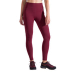 A person wears high-waisted, maroon La Sportiva Cosmosis Leggings Women's and black hiking shoes, standing against a white background; only the body from the shoulders down is visible.