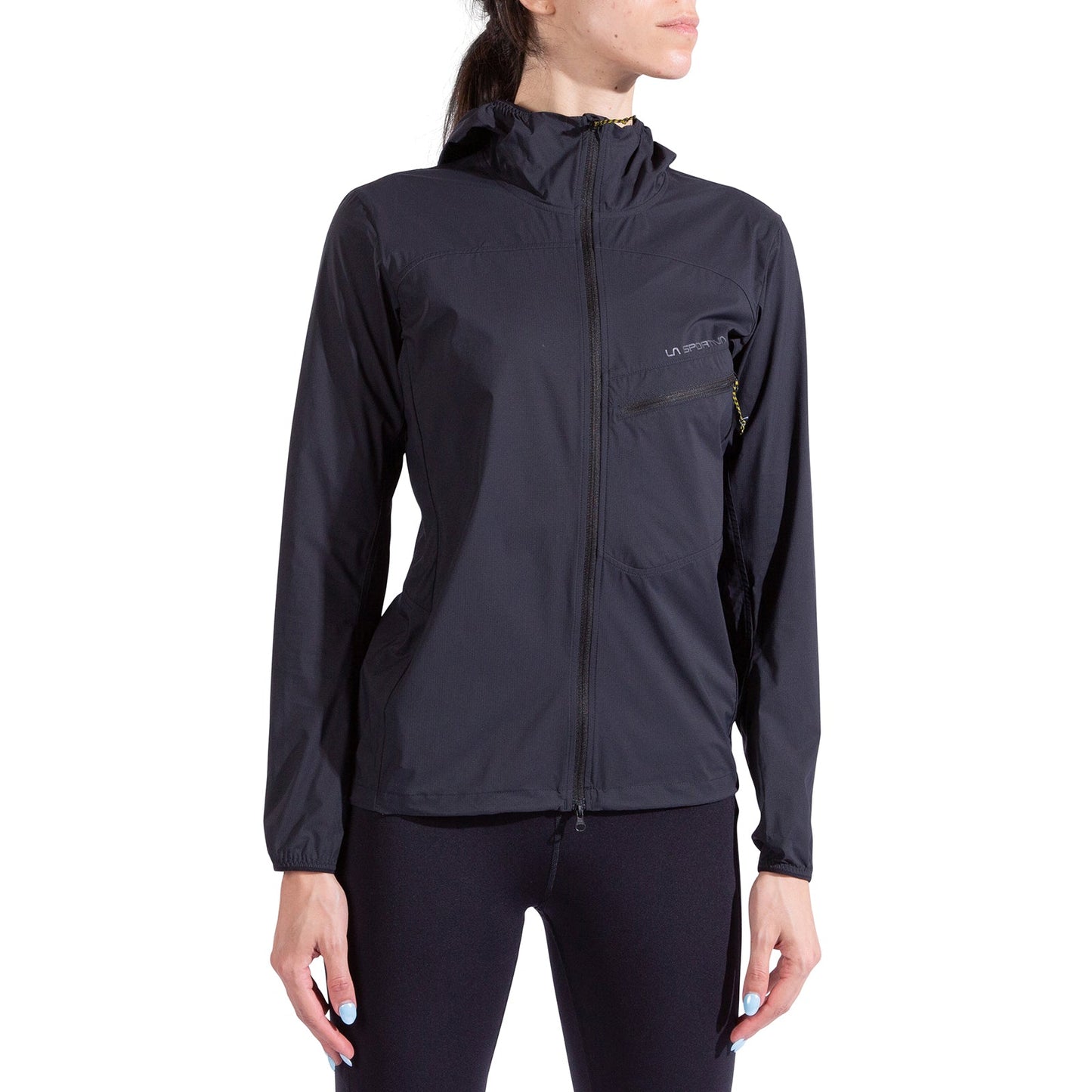 A woman models the La Sportiva Freeway Wind Jacket Women's with black leggings, standing relaxed and facing slightly right against a plain white background.