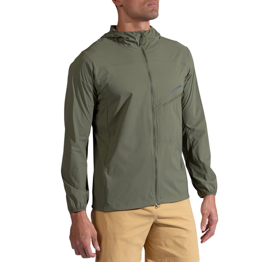 A man wears the La Sportiva Freeway Wind Jacket Men's in light olive green with a hood, chest pocket, and elastic cuffs, paired with tan shorts against a white background. This jacket delivers stylish, functional wind protection.