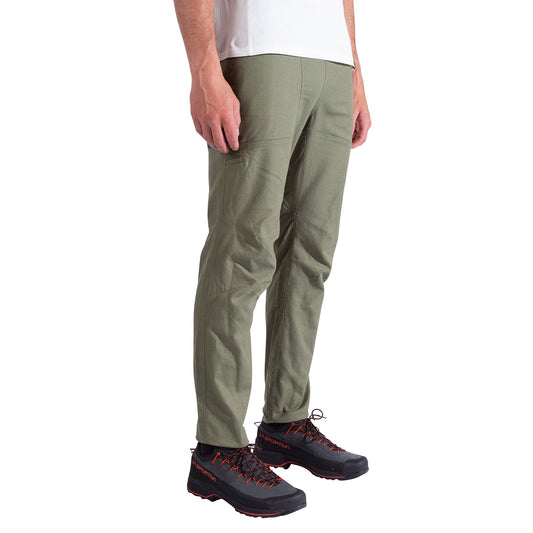 A person wearing La Sportiva Bolt Pants Men's in olive green, a white shirt, and black hiking shoes with red laces stands against a white background. Only the lower half of the body is visible.
