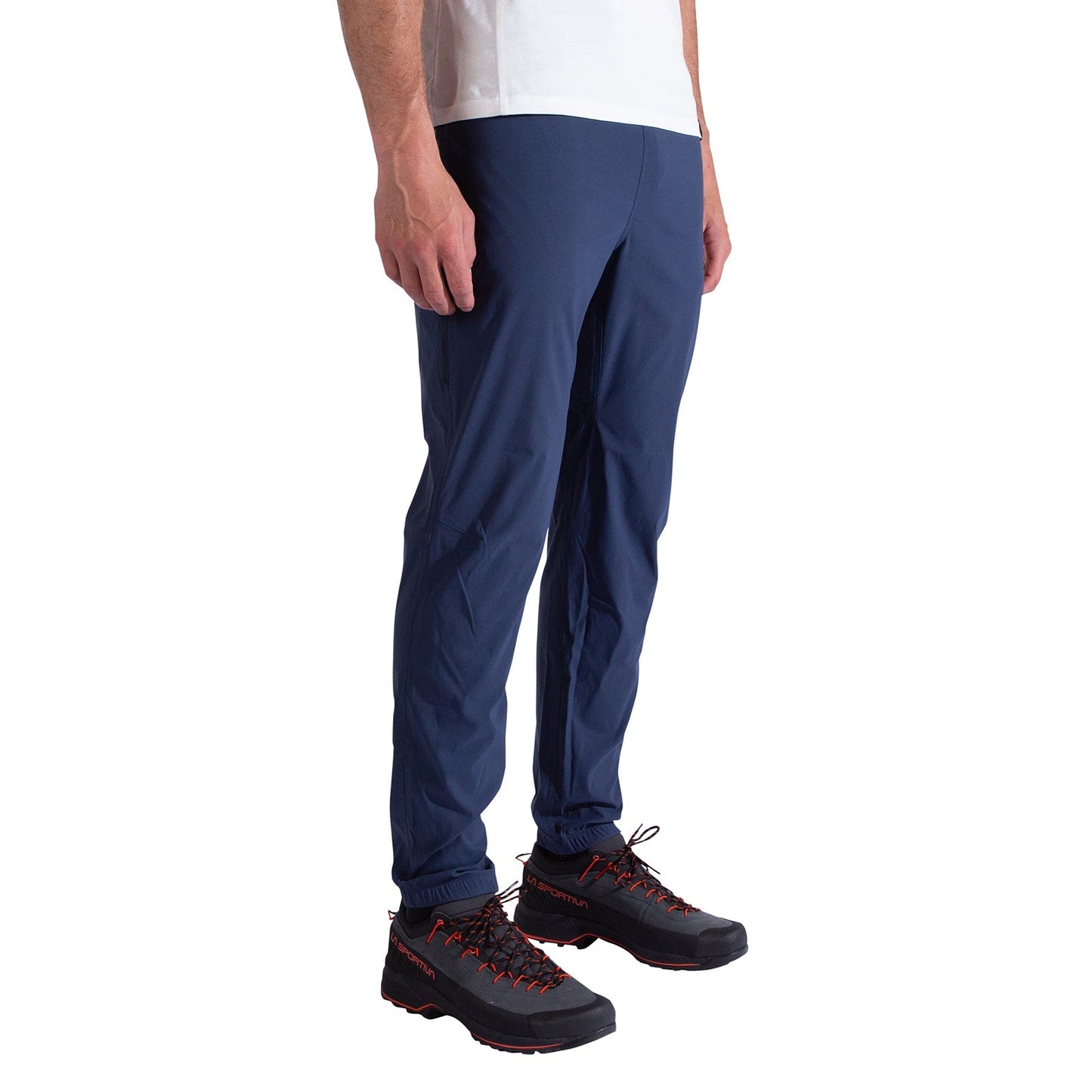A person models La Sportiva Gambit Pants Men's in blue, paired with a white T-shirt and black hiking shoes with red laces, standing against a white background. The top of their head is out of frame.