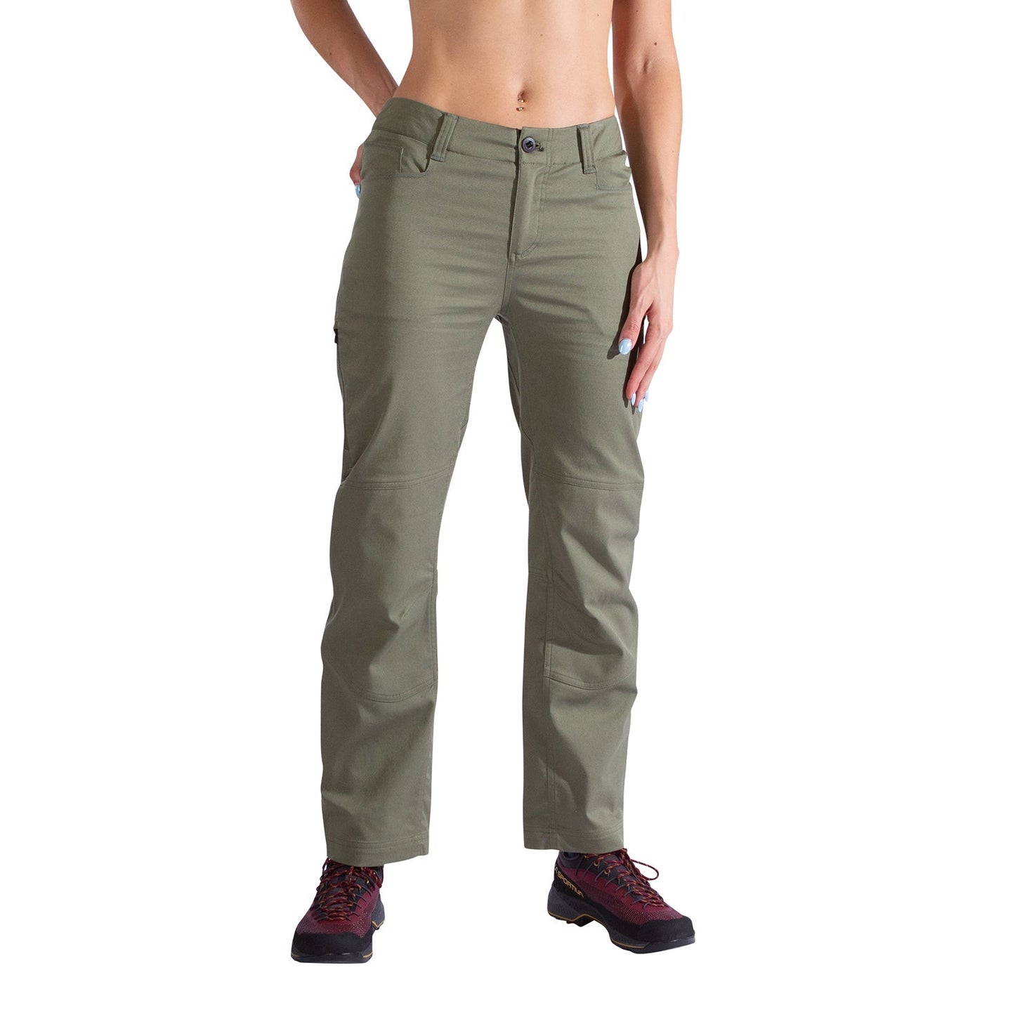 A woman models the La Sportiva Mainliner Pants Women's in olive green twill, standing against a white background with one hand on her hip, finished with burgundy hiking boots.