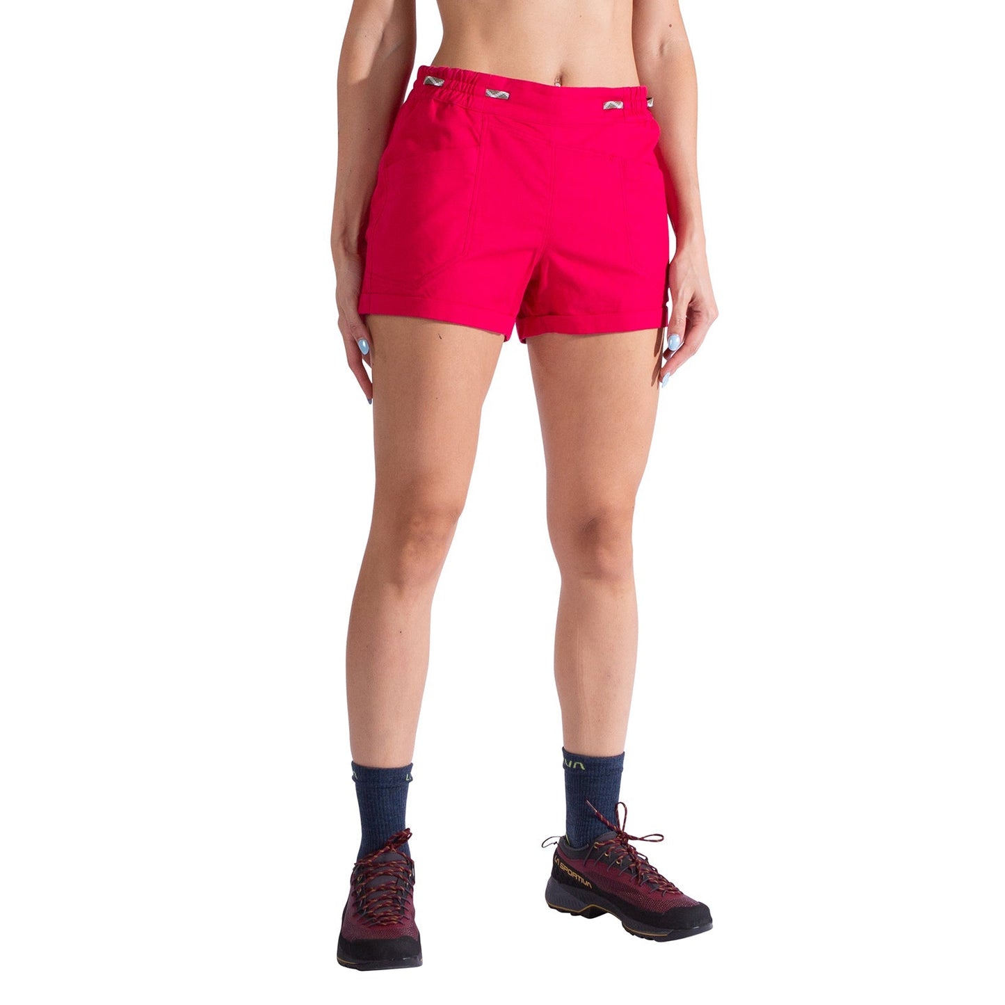 A person models the La Sportiva Bolt Shorts Women's in bright pink, featuring an adjustable waistband. They pair the shorts with navy socks and black hiking shoes, standing against a plain white background with their upper body cropped out.
