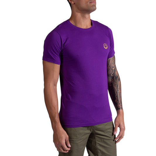 A man wears the La Sportiva Climbing on the Moon T-Shirt Men's in purple with a small circular chest logo and olive green pants, standing against a white background. One arm features a tattoo.