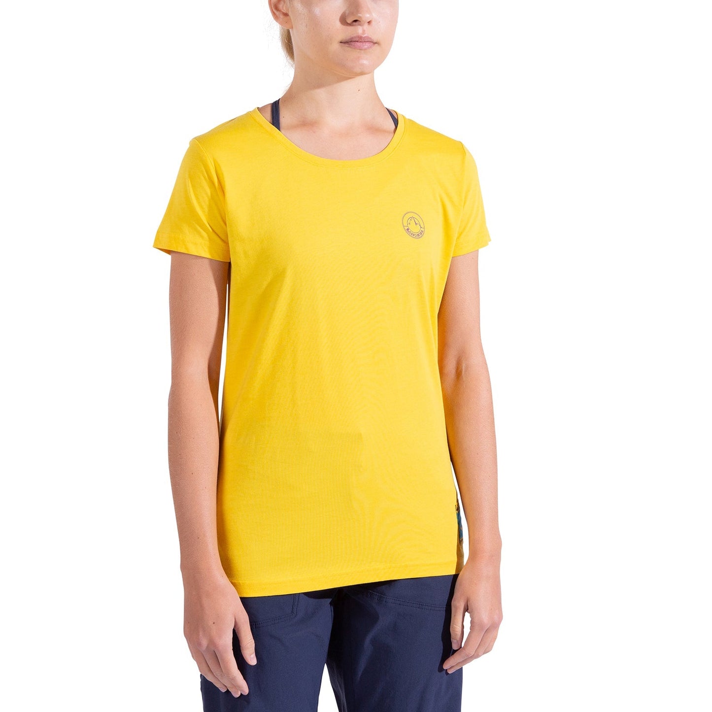 A woman stands against a white background, facing forward with her arms relaxed at her sides, wearing the La Sportiva Climbing on the Moon T-Shirt Women's in plain yellow and dark blue pants. Her face is partially visible.