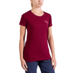 A woman wears a maroon La Sportiva Climb Flower T-Shirt Women's with a small white chest logo and navy pants, standing against a plain white background. Her head is partially out of frame.