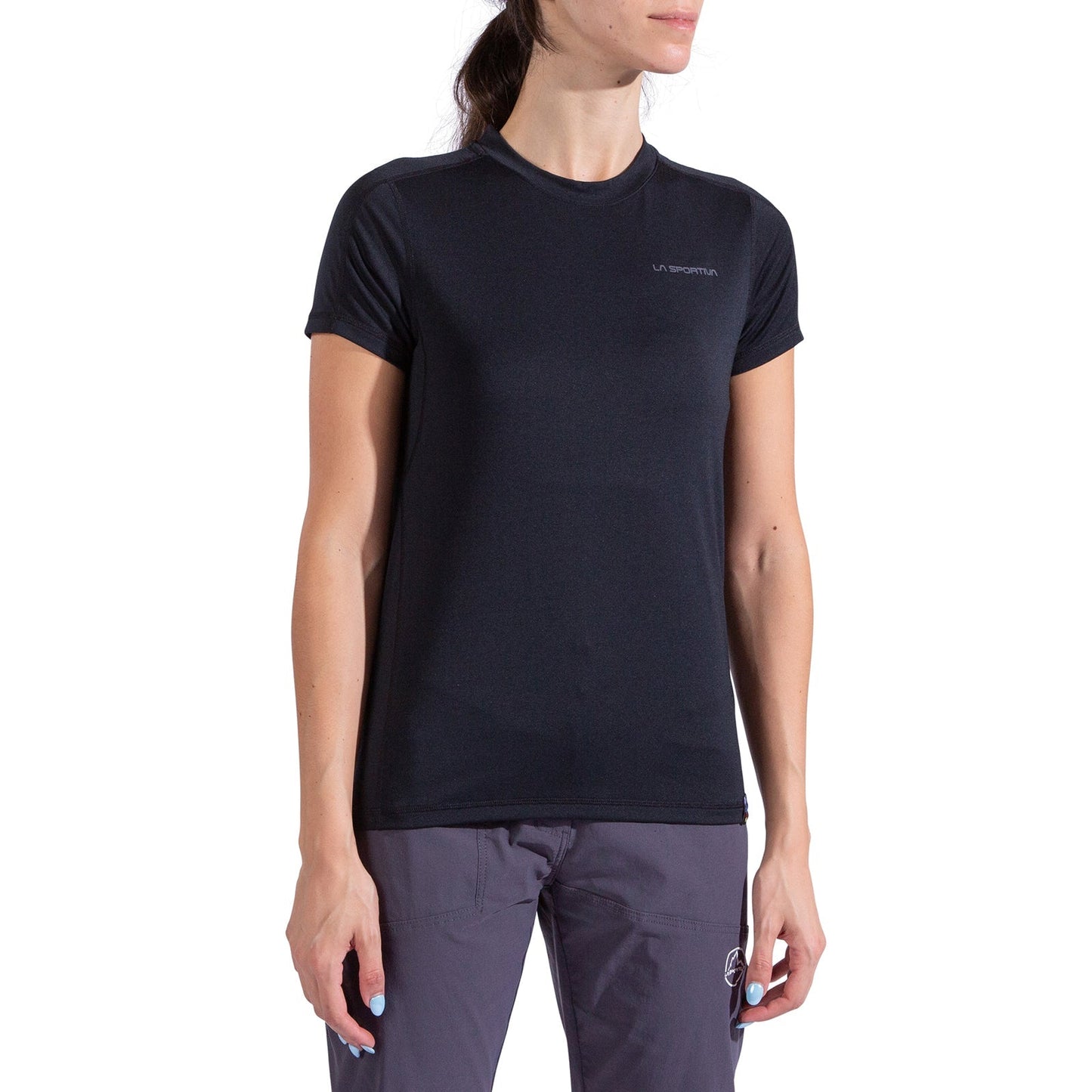 A woman wearing the La Sportiva Just Right T-Shirt Women's in lightweight plain black with a small logo on the left chest and gray pants stands against a white background, her face partially out of frame.