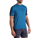 A man wearing the La Sportiva Just Right T-Shirt Men's, featuring blue fabric with dark sleeves and trim, paired with dark shorts, stands against a white background.