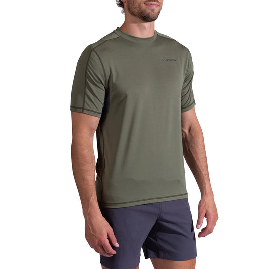A man wearing the La Sportiva Just Right T-Shirt Men's in olive green with short sleeves and dark shorts stands against a white background.
