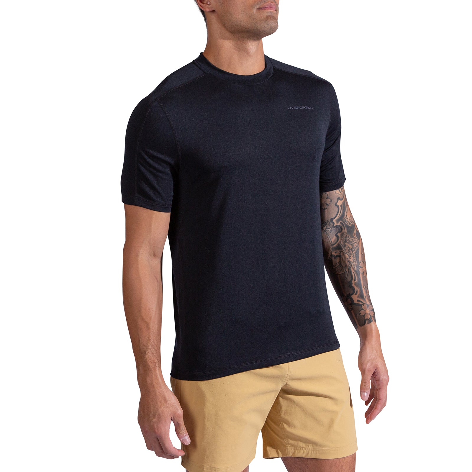 A person wears the La Sportiva Just Right T-Shirt Men's in black with khaki shorts, standing against a white background. One tattooed arm is visible, and their face is partially out of frame.