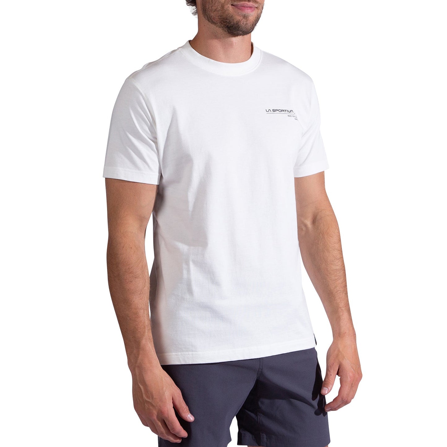 A man wearing a La Sportiva Since 1928 T-Shirt Men's in plain white with a small logo on the left chest and dark shorts, standing against a white background.