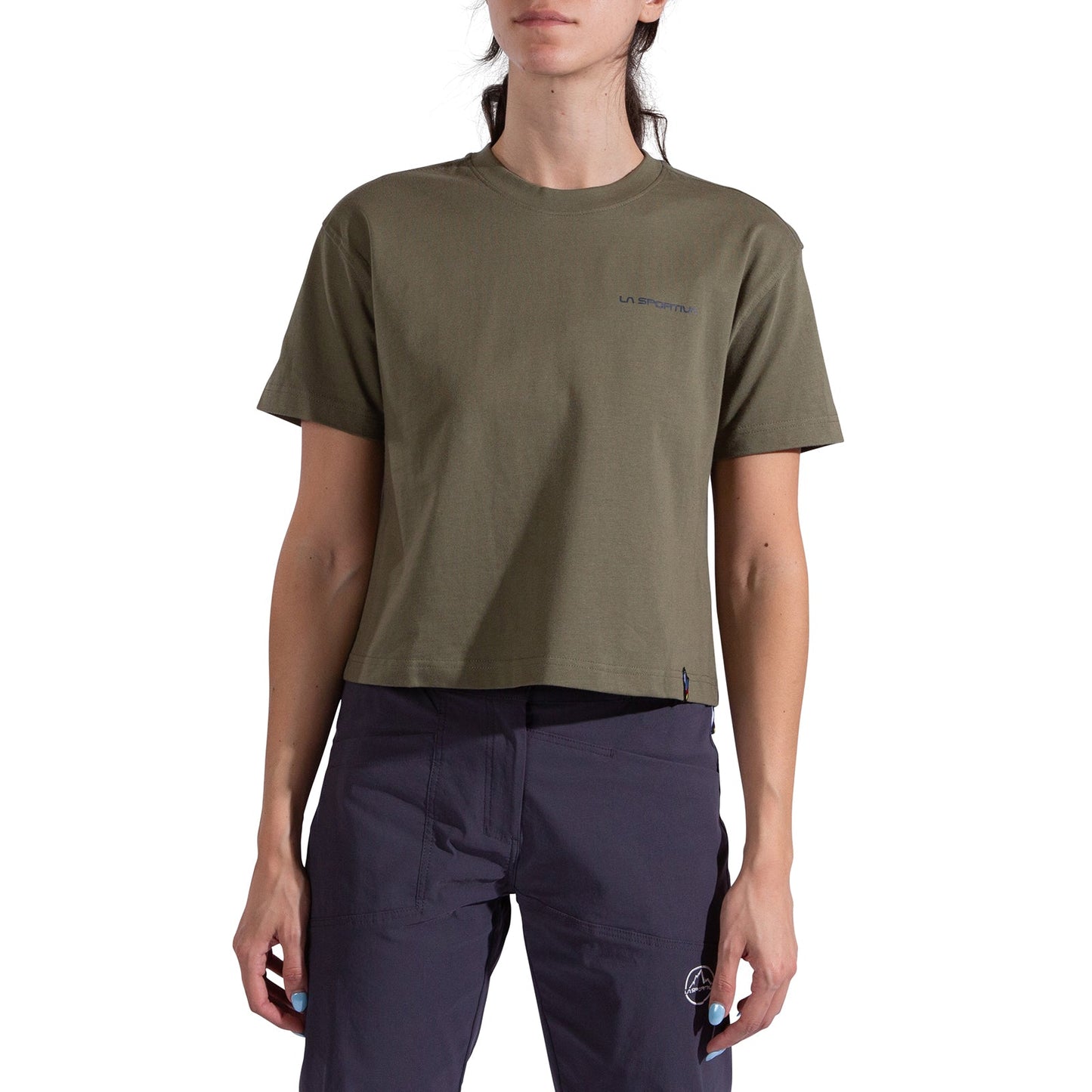 A person wears the La Sportiva Trilogy Crop T-Shirt Women's in olive green, a heavyweight organic cotton tee with a small left chest logo, paired with dark pants against a white background, their head partially out of frame.
