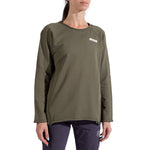 A woman wears the La Sportiva Tufa Sweater Women's in olive green, featuring a small white logo on the chest, and dark pants. She stands against a white background with her face partially out of frame.