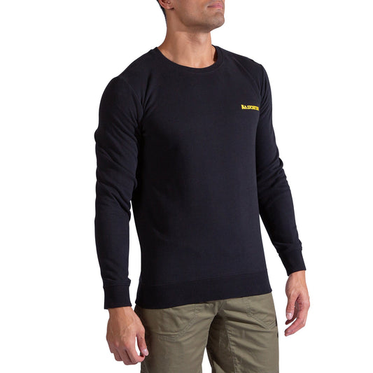 A man wearing the La Sportiva Climbing on the Moon Sweatshirt in black, featuring a small yellow logo on the left chest, and olive green pants, stands against a white background.