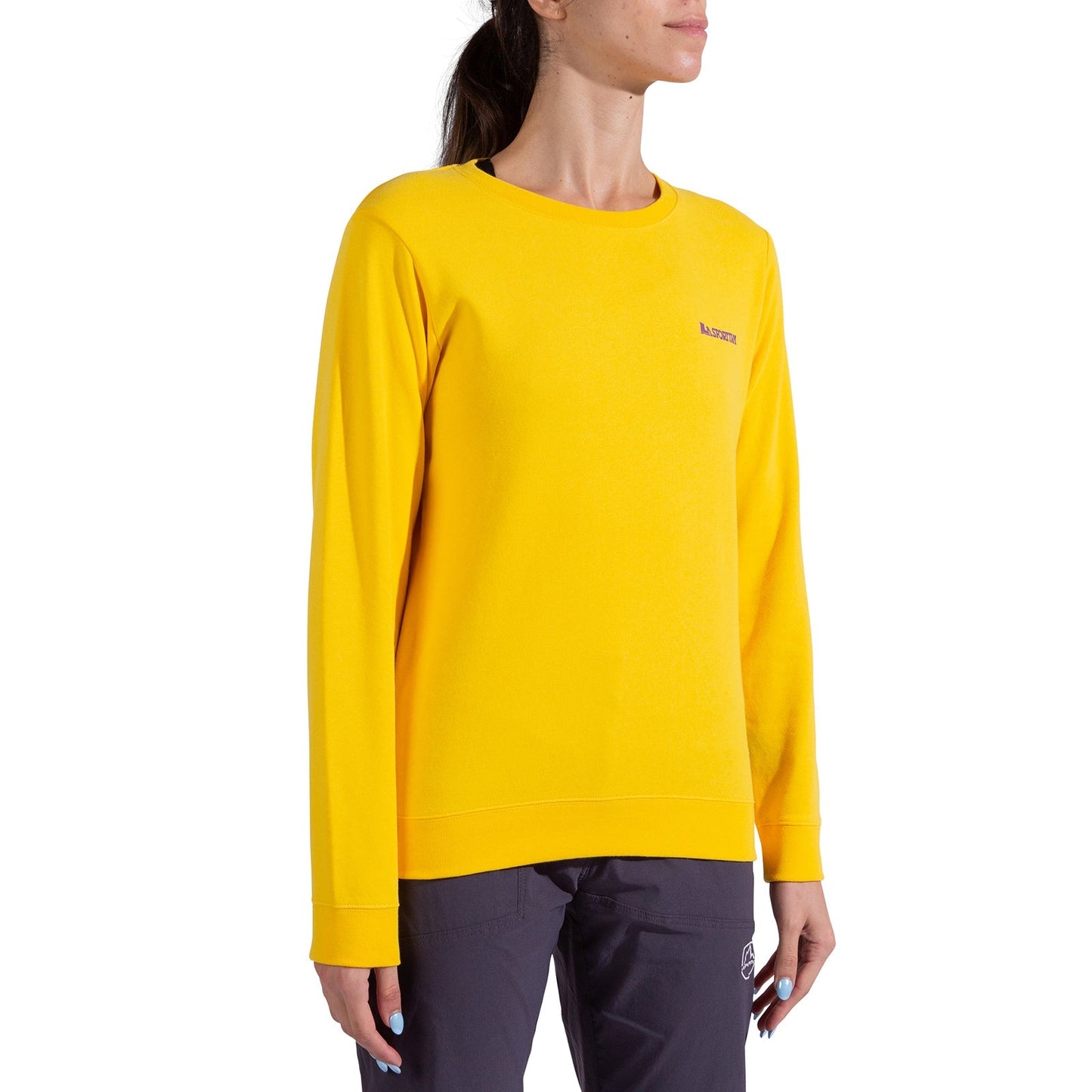 A woman stands against a white background wearing the La Sportiva Climbing on the Moon Sweatshirt Women's in bright yellow with subtle chest text, paired with dark pants.