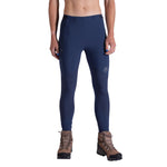 A person is wearing La Sportiva Camino Tight Pants Women's in dark blue with brown hiking boots, standing against a white background. The image shows the pants cropped from the chest down.