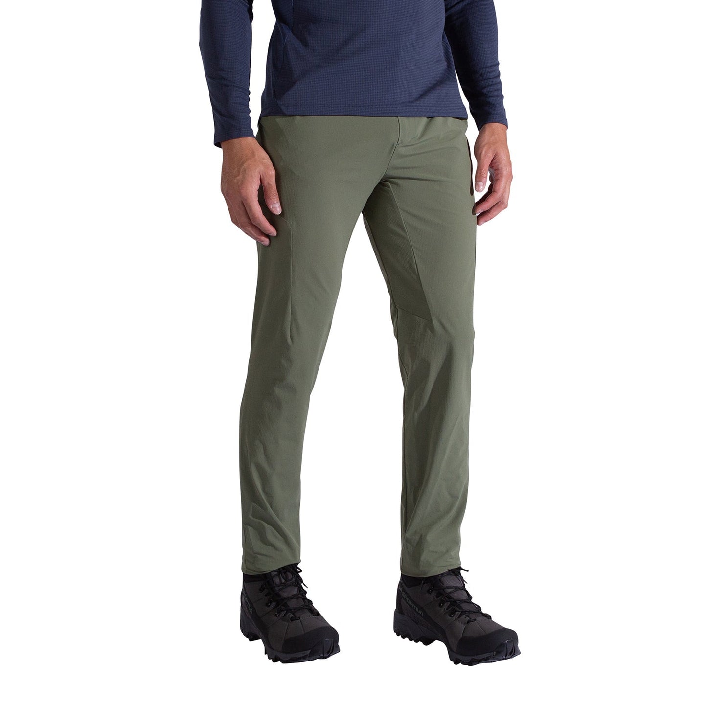 A person wears La Sportiva Trail Guard Pants Men's in olive green, with a navy long-sleeve shirt and black hiking boots, standing against a plain white background—ideal for trail enthusiasts.