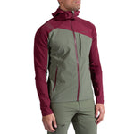 A person wearing the La Sportiva Aequilibrium Speed Jacket Men's in olive green and maroon, with a front zipper, chest pocket, and hood, stands against a plain white background.
