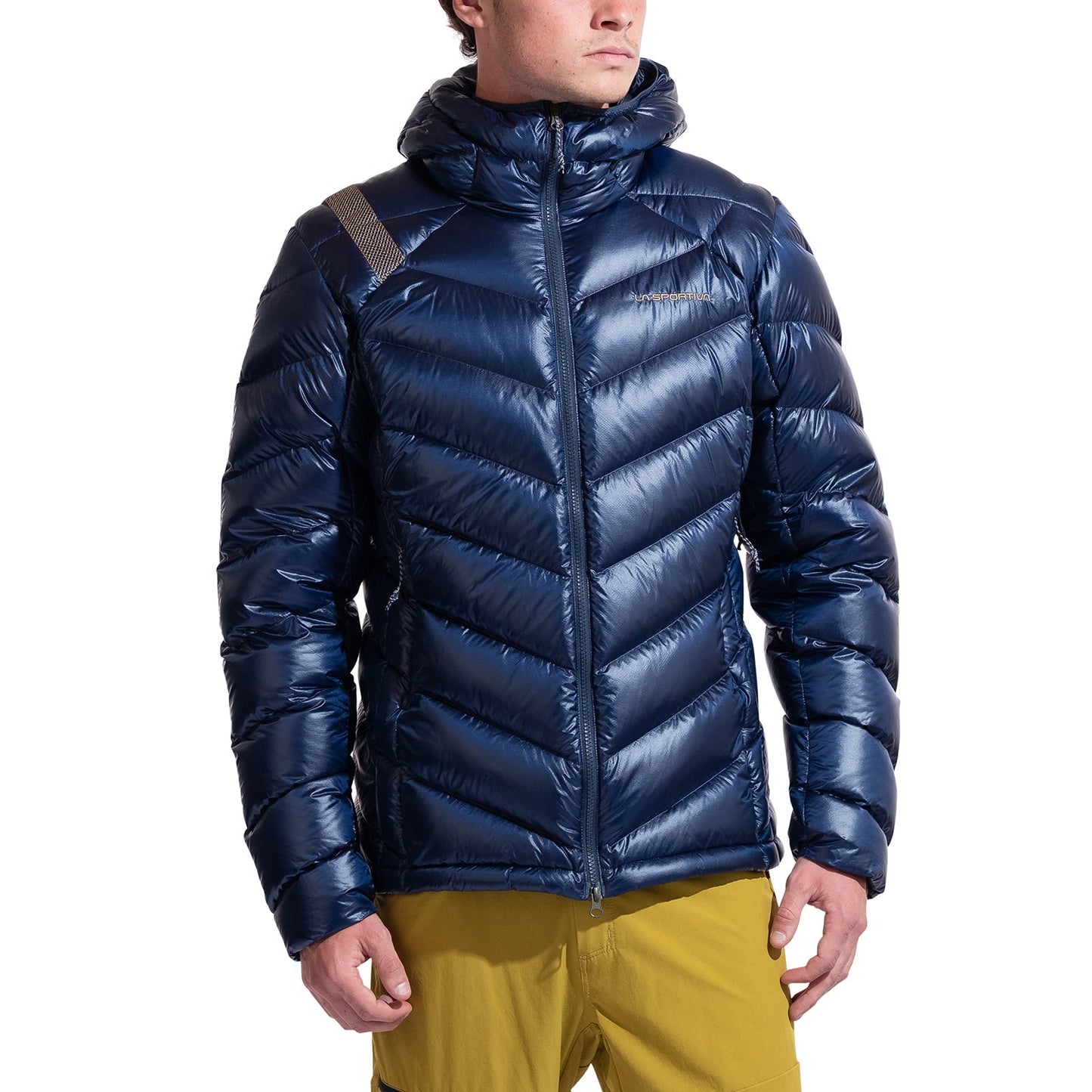 A man in a shiny, dark blue La Sportiva Lumina 300 Down Jacket with a hood and yellow pants stands slightly turned to the side against a white background.